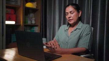 Massaging sore hands from using laptop, Asian woman using laptop at home to work overtime at night, working by typing on laptop for a very long time, trying to work overtime until it hurts when Hand video