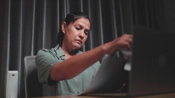 Woman in home office checking notebook, reviewing or planning an article, laptop and freelancer for journalists, proofreading, working on stories at home, looking at schedule in advan video