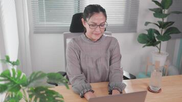 Woman sitting working at wooden table using laptop notebook looking at text typed on screen Happy woman chatting on computer, browsing the internet, social media, studying or working online at home. video