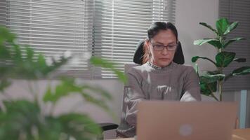 Asian woman writing on laptop in notebook, working from home, studying, studying information, searching online on internet video