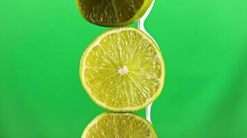 Close up of lime fruits being covered by toxic white liquid paint isolated on a green chroma key background. Stock clip. Concept of ecology and food waste. video