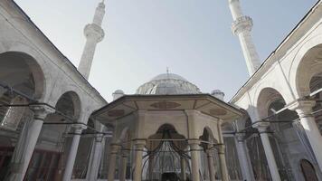 Turkey, Istanbul - July 14, 2022. Beautiful mosque with minarets as historical monument. Action. Bottom view of courtyard of mosque with towering minarets. Beautiful minarets rise into clear sky video