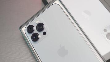 New York, Usa - June 29, 2022. Close up of iphone smartphone with three cameras lying on a table. Action. New smartphone near the box. video