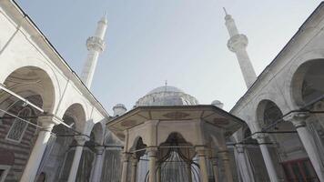 Turkey, Istanbul - July 14, 2022. Beautiful mosque with minarets as historical monument. Action. Bottom view of courtyard of mosque with towering minarets. Beautiful minarets rise into clear sky video