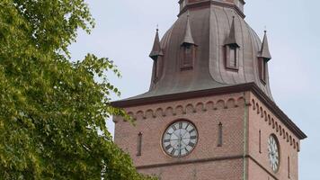 Norway, Oslo - August 30, 2022. View of cathedral tower with clock. Action. Beautiful view from below of cathedral clock and green tree. Oslo Cathedral video