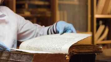 The master is restoring an old book. Stock footage. Close up of a book restorer hands turning pages slowly. video