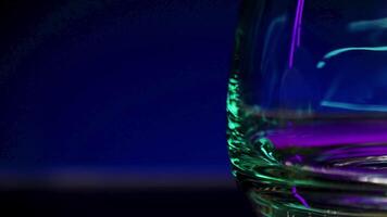 Close up of empty transparent glass with the reflection of lights. Stock clip. Wall with colorful illumination of a night bar. video