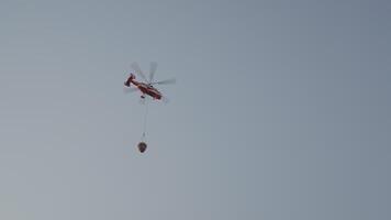 Bottom view of rescue helicopter. Action. Helicopter is flying with bucket to extinguish fire. Fire plane with water for forest fires video