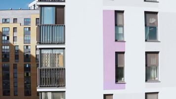 Panoramic view of facade of residential building. Stock footage. View of windows of modern apartment building on sunny day. Beautiful facade with windows of residential building in modern complex video