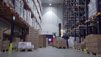 Russia Moscow - February 24, 2022. Warehouse worker driver in uniform moving cardboard boxes by forklift stacker loader. Creative. Forklift pallet with boxes in large modern warehouse. video