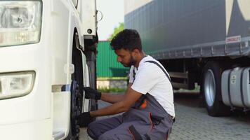 Indian truck driver using socket wrench while changing tire on the road video