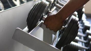 Strong well built black bodybuilder lifting dumbbell weights getting ready for exercise in fitness video