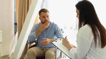 Psychotherapy consultation. Counselor offering help and support to young man in wheelchair at office video