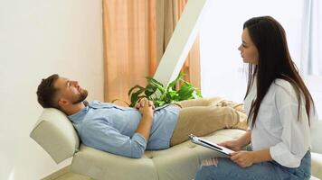 Young man at the psychotherapist, lying on couch, emotionally speaking, discussing with psychotherapist his problems video