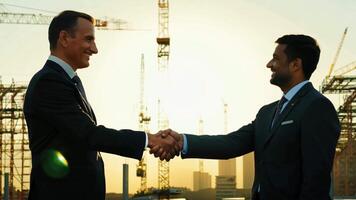 Two Businessmen shake hands on a deal with view of The background of a large construction site has beautiful sunlight. video