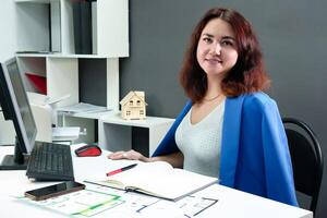 Busy working at a computer in an office, a curly-haired girl in a blue suit conveys a sense of high productivity, efficiency and getting results photo