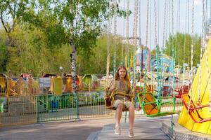 girl sits hesitantly on an amusement park swing, her expression reflecting trepidation and determination as she prepares to conquer her fears on a summer day photo