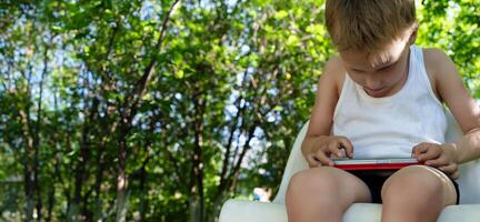 Banner with child captivated by the screen of his smartphone, his posture of a lowered head and slouched shoulders conveying the concerning physical consequences of compulsive mobile device use photo