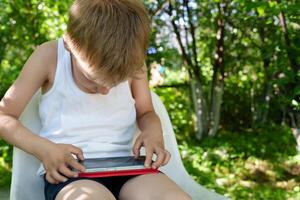Boy engrossed in the content of his smartphone, his drooping head and rounded shoulders suggesting the harmful effects of prolonged mobile device use photo