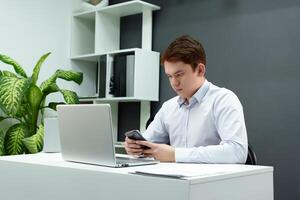 An enterprising man successfully conducts business correspondence over the phone while sitting in front of a computer monitor in a modernly decorated office space photo