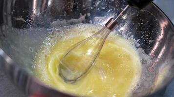metal bowl contains frothy, whisked eggs, with a whisk visible in motion, capturing the dynamic process of preparing a culinary dish or baking mixture photo