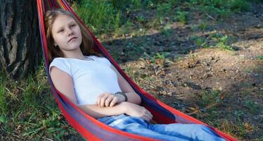 thoughtful teenage girl reclines in a hammock, her introspective gaze suggesting she is navigating the emotional complexities of growing up with quiet contemplation photo