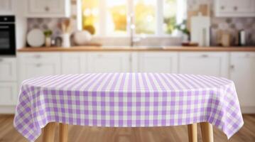 Empty table with pastel purple and white checkered tablecloth top on blurred kitchen background photo