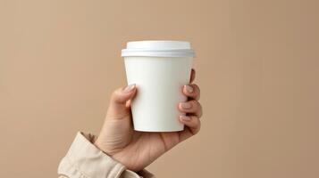 Woman's hand holding paper cup with coffee isolated on empty beige background with space for text or inscriptions. photo