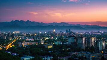 An expansive view of Almaty's cityscape at dusk with vibrant lights and mountains visible. photo