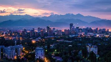 An expansive view of Almaty's cityscape at dusk with vibrant lights and mountains visible. photo