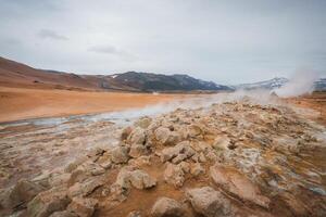 Hverir Geothermal Area with Steam Fumaroles and Snow-Capped Mountains in Iceland photo