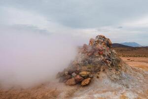 Geothermal Steam Vent with Snow-Capped Mountains in Iceland's Rugged Landscape photo