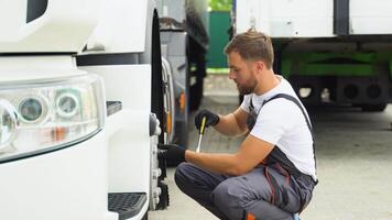 Truck driver using socket wrench while changing tire on car service video