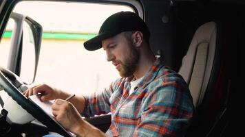 Delivery man with cardboard box checking list in truck. Courier checking list on clipboard. Deliveryman sitting in truck and checking the delivery list. Right hand drive car video
