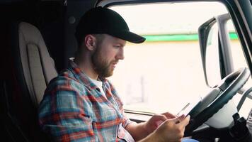 Delivery man with cardboard box checking list in truck. Courier checking list on clipboard. Deliveryman sitting in truck and checking the delivery list video