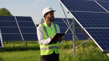 Young indian engineer in special uniform stands on background of solar panels and holding documents video