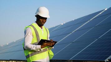Black engineer using tablet pc near solar panel video