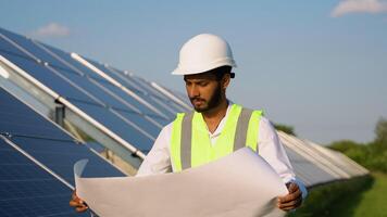 Portrait of indian technologist in uniform with protective helmet. Businessman looking at paper plan placing solar panels video