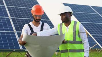 Two diverse multiracial technical engineers review plan on paper and discuss video