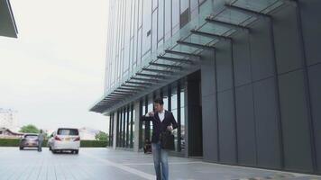 A businessman looks at his watch in a hurry as he runs to catch up with the clock behind a tall building. video