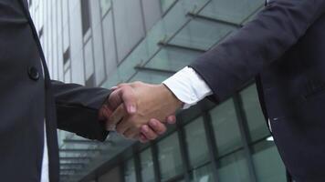 Businessmen's hands shaking hands in business connection behind tall building video