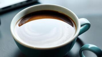 A cup of coffee placed on a modern office desk, alongside a laptop and a notepad, suggesting a moment of refreshment during work. video