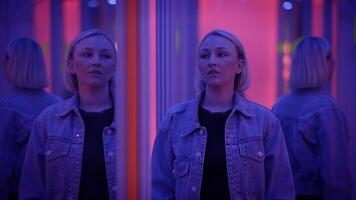 Woman exploring a mirror maze with neon lights creating an enigmatic and immersive atmosphere video
