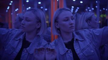 A woman in a mirror maze with neon lights and reflecting patterns in a futuristic setting video