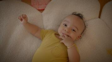 A young baby dressed in a yellow onesie is peacefully resting on a soft white blanket video