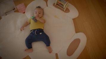 A baby is relaxing on a bearshaped mat with a toy, creating a cute and cozy scene in the nursery video