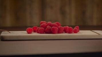 A collection of vibrant red raspberries neatly arranged on a clean white cutting board video