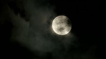 Full Moon casting a serene glow over the night sky, illuminated by dramatic clouds video