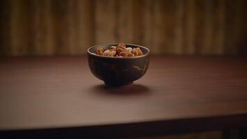 A wooden bowl filled with an assortment of mixed nuts displayed on a rustic wooden table video