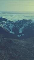 large snow patch left over on the volcanic rock field of a mountain in summer video